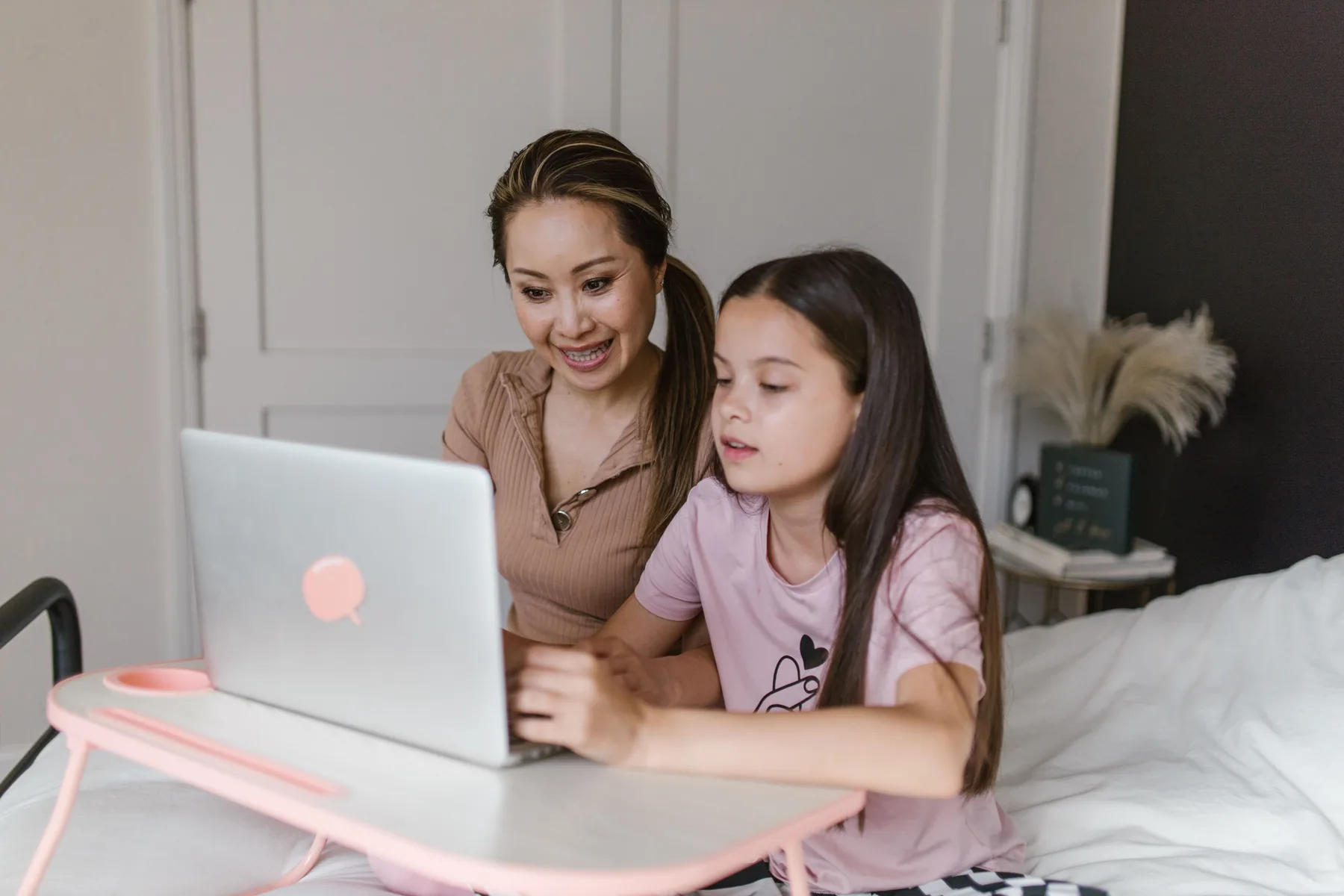 A parent and child learning together on a laptop at home