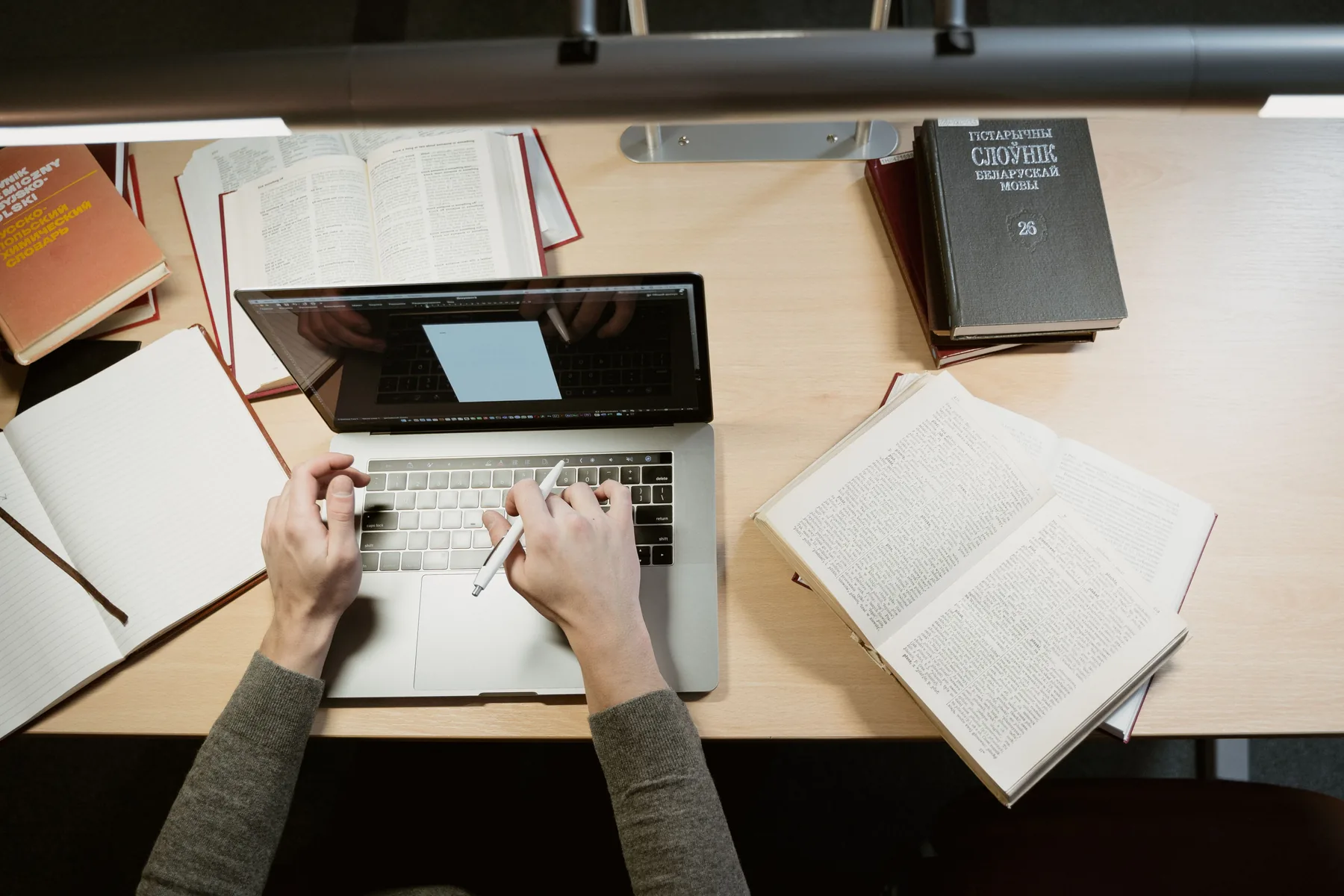 A study desk with a laptop, notebooks and books